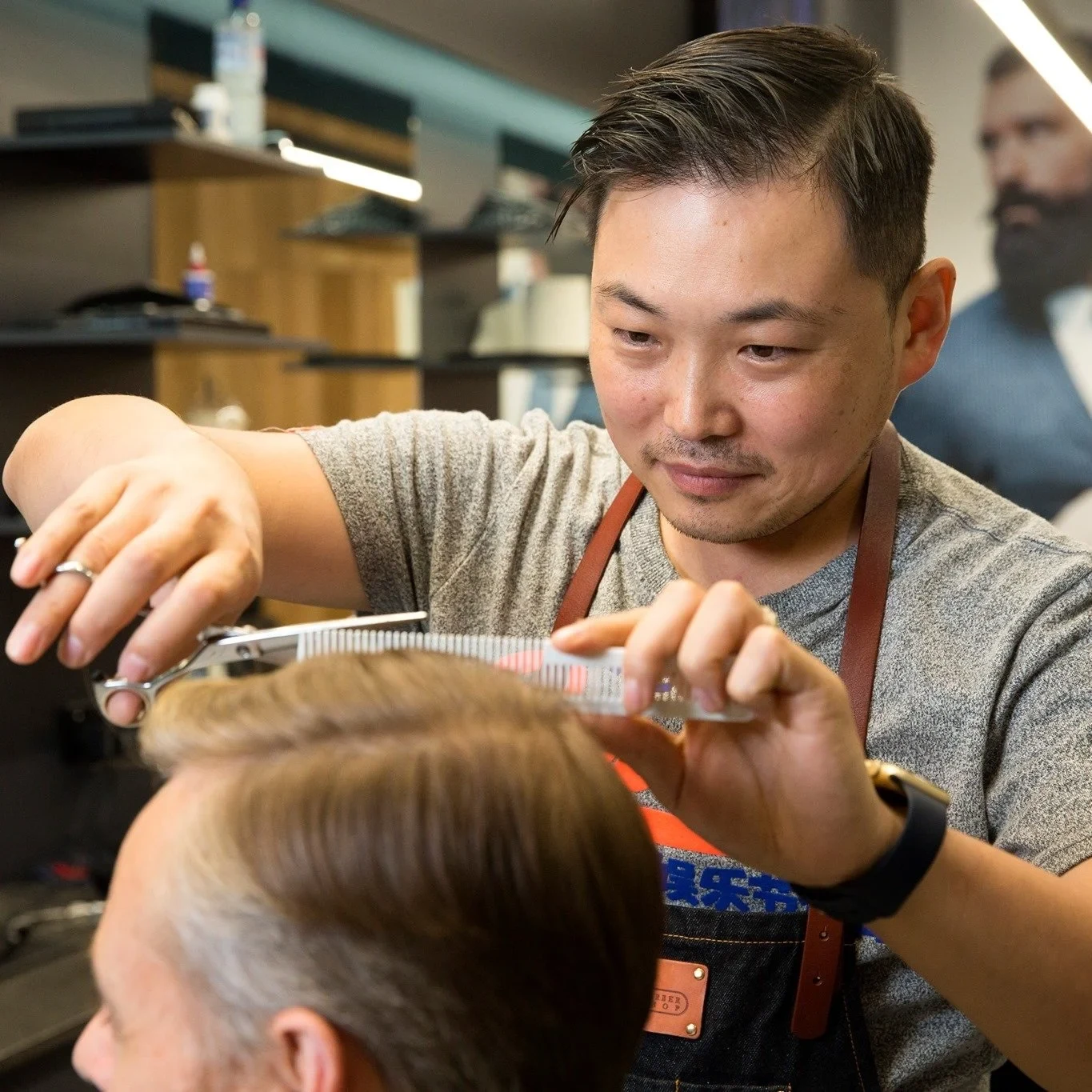 Jay smiling as he cuts a customer's hair with scissors and comb